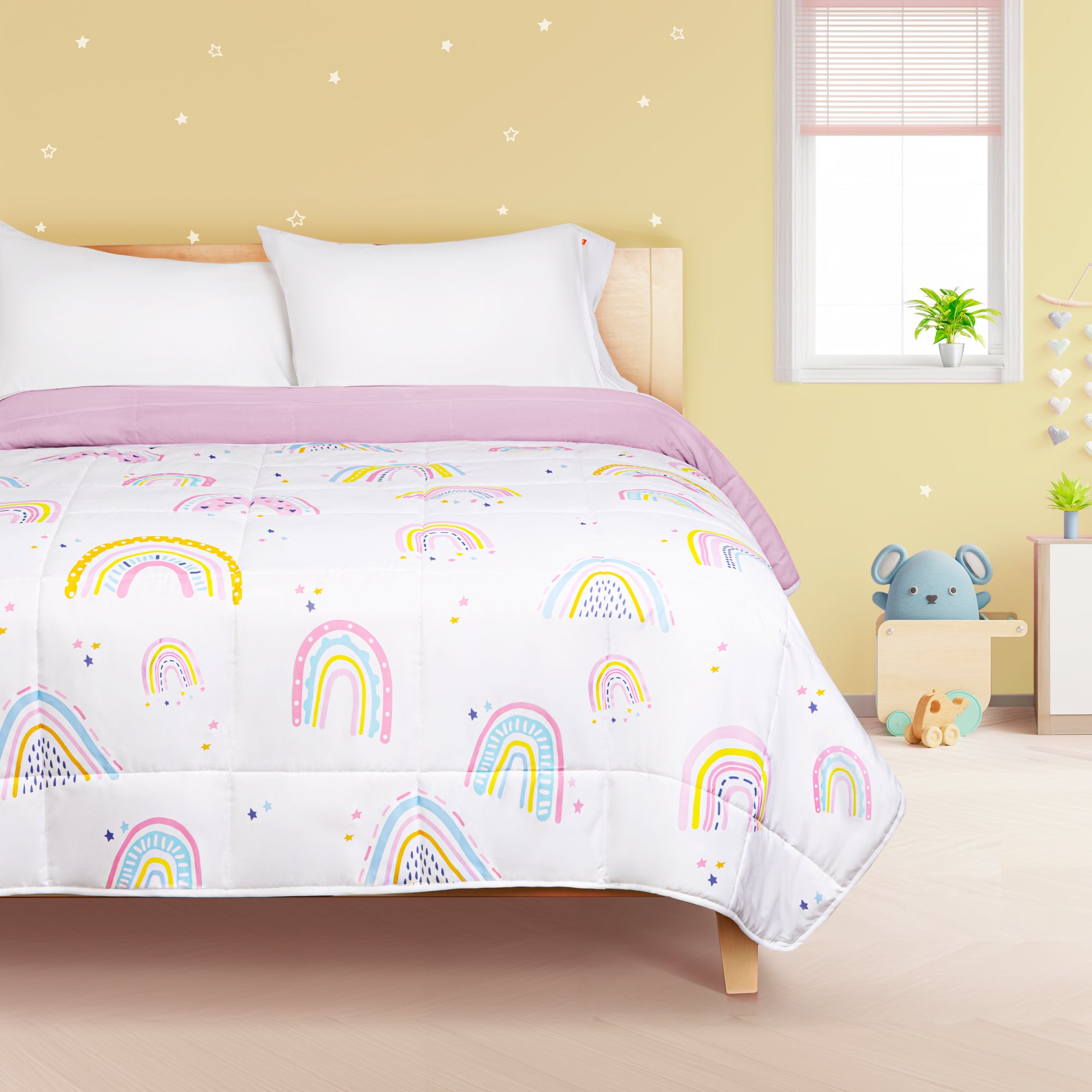 Edredón ligero infantil, relleno de microfibras recubiertas en gel, con diseño arcoíris y reverso rosa, ideal para camas individuales y matrimoniales.